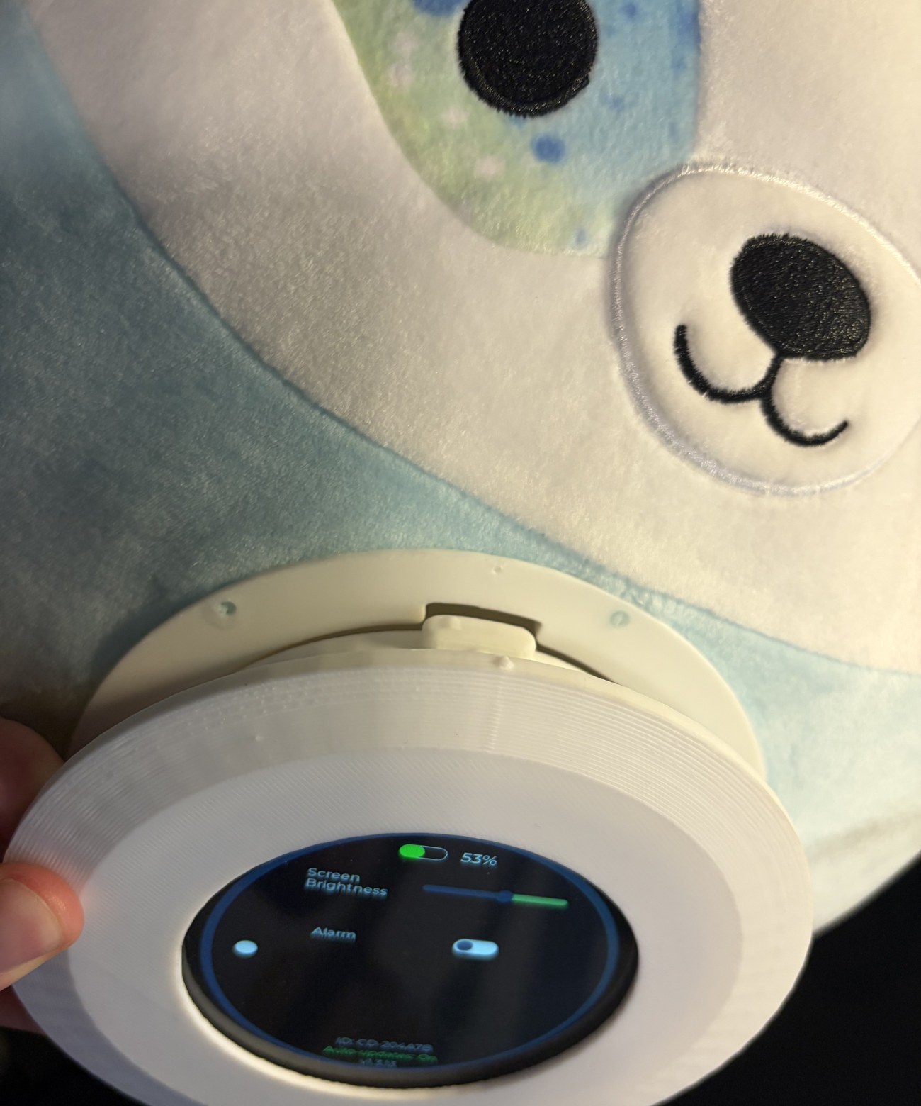 Lining up the device tabs with the stuffed animal's enclosure before twisting to lock