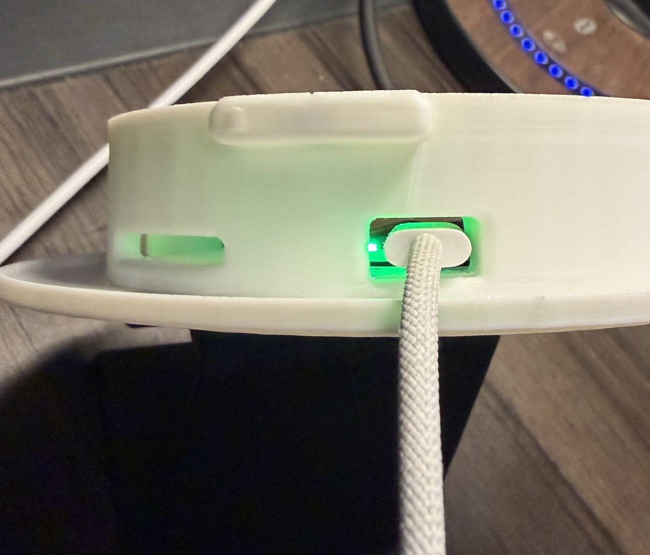 USB-C cable plugged into the charging port, with the green charging LED glowing through the case